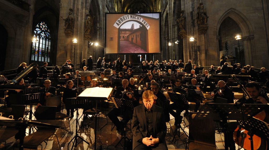 An image of the Terezin concentration camp entrance in German-occupied Czechoslovakia, with a sign reading ‘Arbeit Macht Frei,’ is projected on a screen during a performance of Giuseppe Verdi’s Requiem Mass at St. Vitus Cathedral in Prague, Czech Republic on Thursday, June 6, 2013. (photo credit: AP Photo/CTK, Stanislav Zbynek)